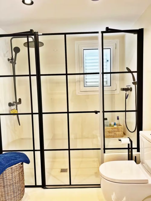 Moderno cuarto de baño con ducha de cristal con patrón de rejilla negra en apartamento frente al mar en Fuengirola