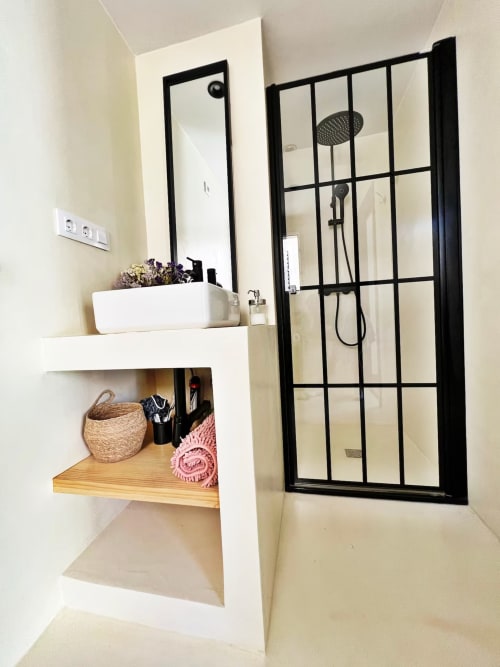 Moderno baño en apartamento frente al mar en Fuengirola con ducha de mampara negra y mueble flotante blanco