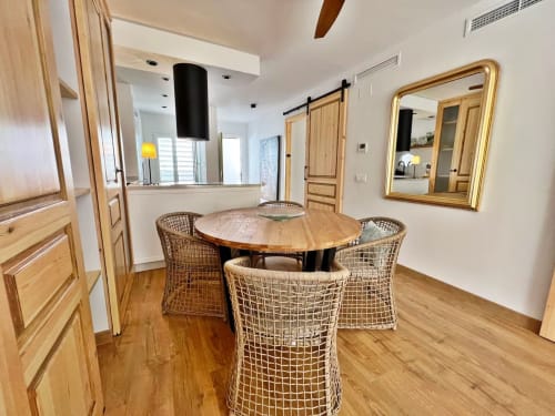 Comedor de apartamento moderno en la playa con mesa de madera, sillas tejidas y cocina abierta en Fuengirola