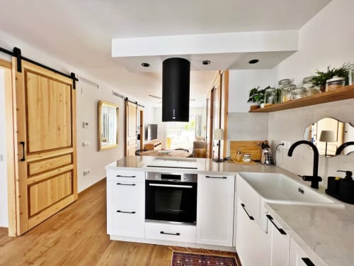 Cocina moderna en apartamento de playa en Fuengirola con muebles blancos, detalles negros, puertas correderas de madera y vistas a la ciudad