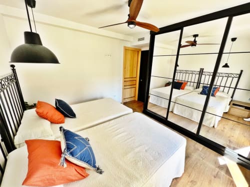 Moderno apartamento de playa en Fuengirola con camas gemelas, marcos metálicos negros, ventiladores de techo de madera y armario espejado