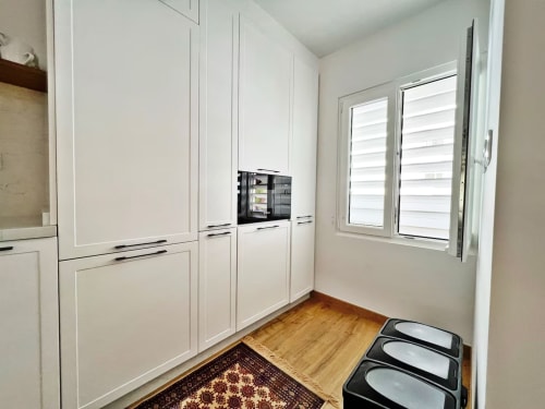 Cocina blanca moderna con electrodomésticos integrados y suelos de madera en apartamento frente al mar, Fuengirola