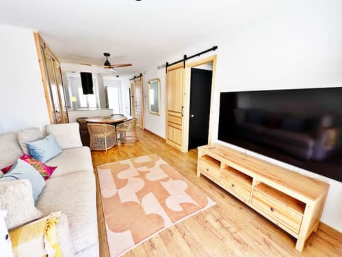 Moderno apartamento de playa en Fuengirola con muebles de madera, televisor de pantalla plana y alfombra beige con patrón