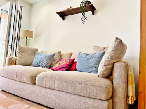 Acogedor sofá beige con cojines coloridos en moderno apartamento de playa en Fuengirola por Grupo Inmo House