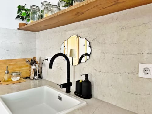 Lavabo moderno con grifo negro, espejo decorativo y acabado en mármol en apartamento de playa en Fuengirola