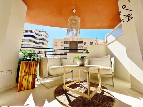 Balcón de apartamento en primera línea de playa en Fuengirola con zona de descanso, techo naranja, lámpara de araña y vistas a la ciudad