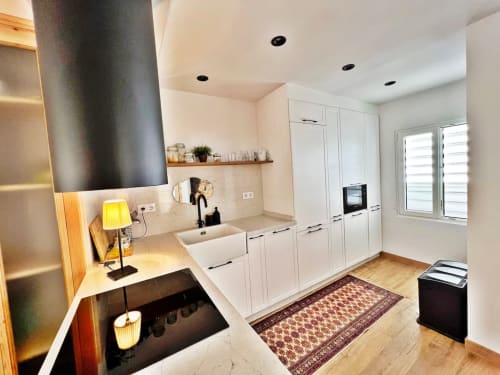 Moderna cocina blanca en apartamento de playa en Fuengirola con electrodomésticos de acero inoxidable y suelo de madera