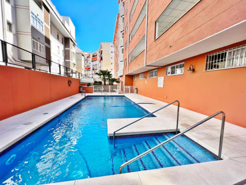 Piscina al aire libre con zona de descanso en complejo de apartamentos frente al mar en Fuengirola
