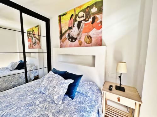 Dormitorio moderno en apartamento de Fuengirola con cama con dosel, ropa de cama azul, cabecero blanco y arte colorido sobre la pared