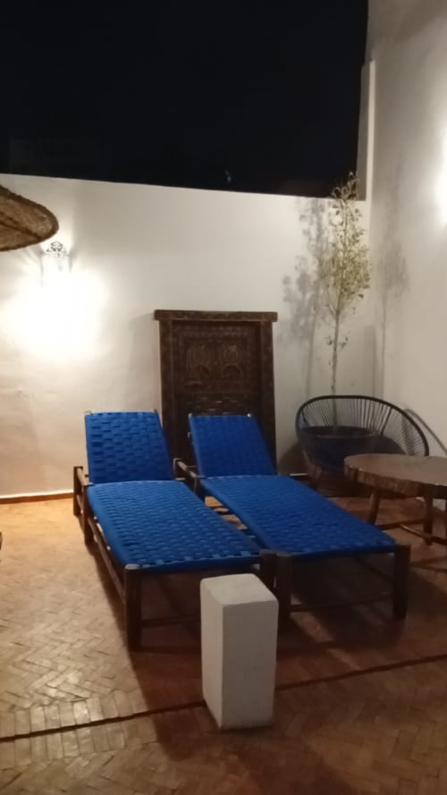 Chaises longues bleues dans la cour intérieure du Riad Le Village Mogador à Essaouira, hôtel aux murs blancs et décor traditionnel