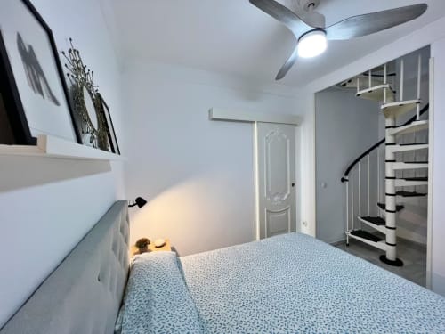 Moderno estudio en Fuengirola con ventilador de techo, escalera de caracol y mobiliario contemporáneo