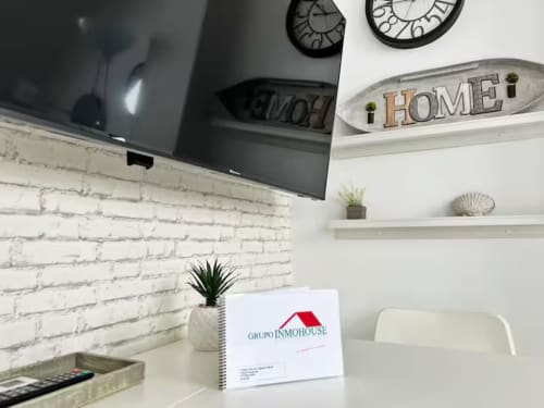 Moderno apartamento de playa en Grupo Inmo House, Fuengirola, con pared de ladrillo blanco, TV empotrada y decoración del hogar