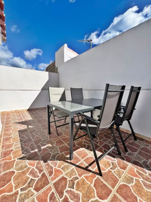Moderna terraza en azotea con mesa de comedor y sillas con vistas a Fuengirola, España. Balcón de apartamento con vista a la ciudad.