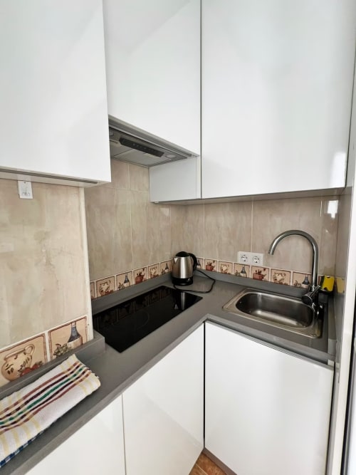 Cocina compacta en apartamento frente al mar, Fuengirola, con armarios blancos, azulejos y fregadero de acero inoxidable