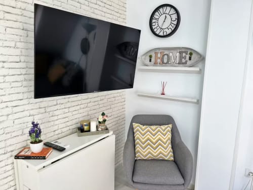 Moderno apartamento de playa en Fuengirola con televisor de pared, sillón gris y detalles decorativos