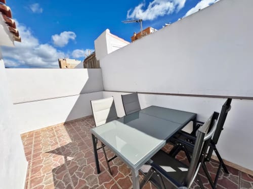 Terraza moderna en azotea con mesa de comedor y sillas, paredes blancas, vistas de la ciudad, apartamento en Fuengirola