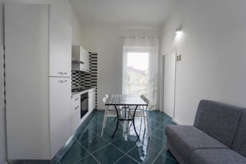 Zona cucina-pranzo moderna nell'appartamento Antico Palazzo del Corso con mobili bianchi, paraschizzi geometrico nero, dining
