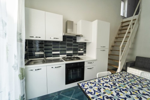 Cucina moderna con i mobili bianchi, rivestimento nero e piano cottura a gas nell'Antico Palazzo del Corso
