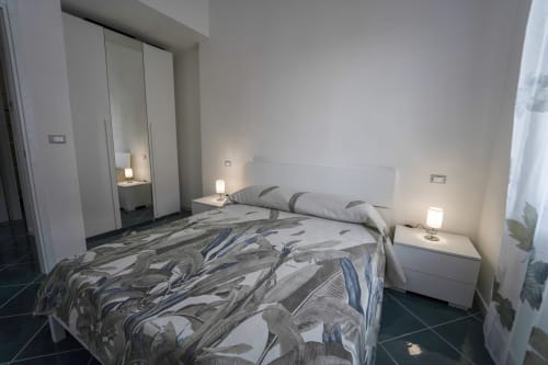 Camera moderna nell'appartamento Levante di Antico Palazzo del Corso, Mirto Crosia, con biancheria a motivi, comodini bianchi e