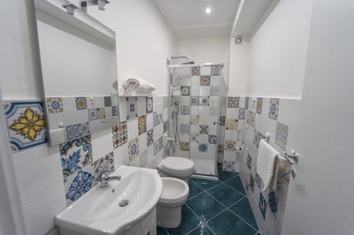 Bagno moderno all'Antico Palazzo del Corso a Mirto Crosia con piastrelle decorative blu e gialle, lavandino bianco, WC e