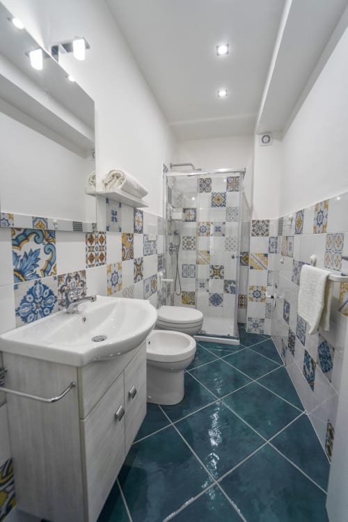 Bagno moderno nell'appartamento Levante di Antico Palazzo del Corso con piastrelle decorative blu e oro, lavabo e wc