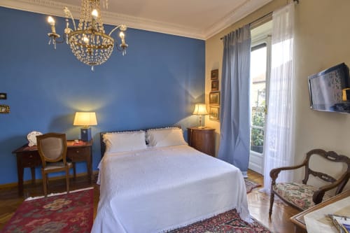 Camera elegante presso l'A Casa Armenia B&B di Torino con parete blu, lampadario in cristallo e vista dal balcone