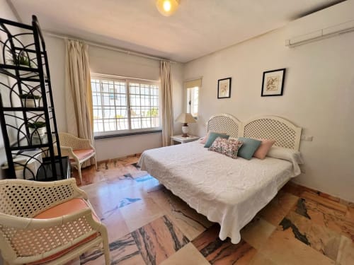 Luminoso dormitorio en apartamento de Fuengirola con cama matrimonial, vistas al jardín y decoración moderna