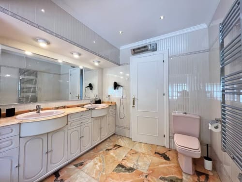 Lujoso baño moderno en apartamento de Fuengirola con doble tocador, suelos de mármol y equipamiento contemporáneo