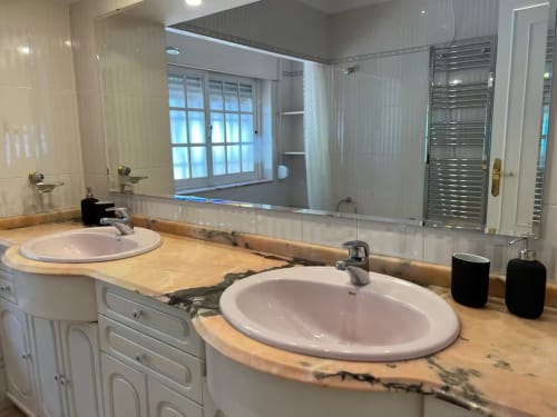 Moderno cuarto de baño en apartamento de Fuengirola con dobles lavabos, encimera de madera, gran espejo y vistas al jardín