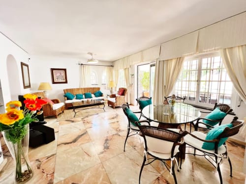 Luminoso apartamento independiente en Fuengirola con suelos de mármol, muebles de mimbre, toques turquesa y vistas al jardín