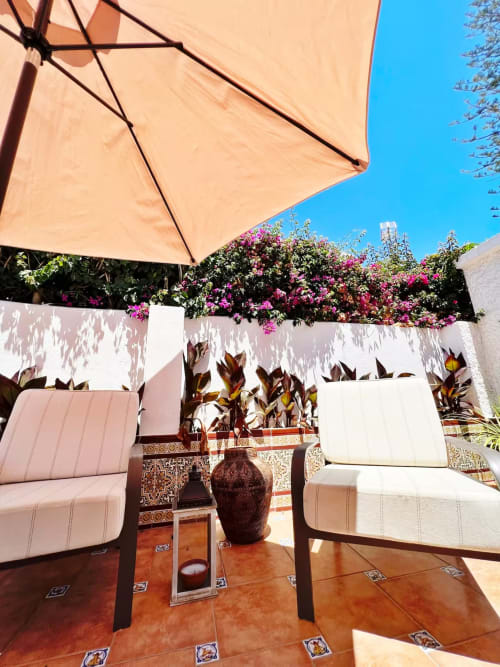 Patio soleado con sombrilla, tumbonas y flores de buganvilla rosa en apartamento de Fuengirola