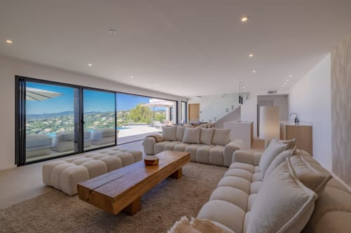 Salon luxueux de la Villa Prestige Azur avec vue mer, sièges crème, table basse en bois et accès terrasse