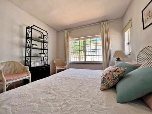 Dormitorio luminoso en apartamento independiente en Fuengirola con cama de matrimonio, vistas al jardín, estantería negra y decoración elegante
