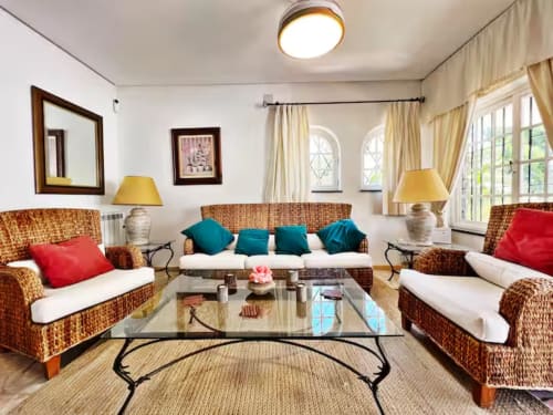 Luminoso salón de apartamento independiente en Fuengirola con mobiliario de mimbre, vistas al jardín y diseño costero español