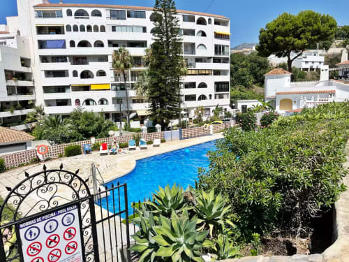 Luminoso apartamento en Fuengirola con vistas a la piscina, jardines frondosos y edificios encalados bajo cielos despejados