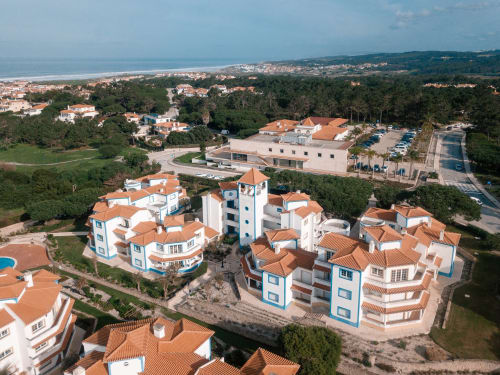 Vista aérea do hotel Be SilverCoast com edifícios brancos, telhados com telhas laranja, jardins verdes e cidade costeira de Serra D'El Rei
