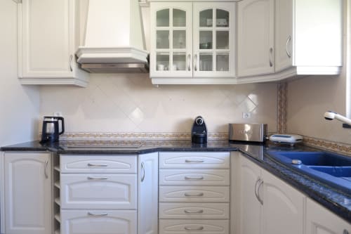 Cozinha moderna branca com bancadas escuras e azulejo decorativo em Casa Lusitania no Be SilverCoast, Serra D'El Rei