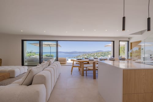 Salon de villa de luxe avec vue panoramique sur la mer, mobilier moderne, salle à manger et paysage côtier méditerranéen