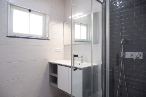 Banheiro moderno do hotel Be SilverCoast com chuveiro, espelho e detalhes contemporâneos em azulejos pretos em Serra D'El Rei