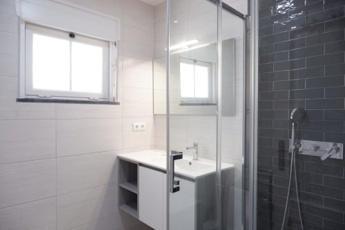 Banheiro moderno com azulejos preto e branco, box de chuveiro em vidro e janela na Casa Lusitania, hotel Be SilverCoast