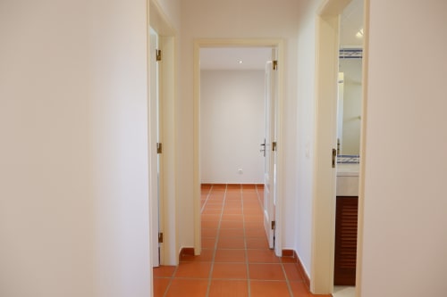 Corredor limpo do hotel Casa Lusitania no Be SilverCoast com piso de azulejo terracota e portas brancas em Serra D'El Rei