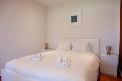 Quarto luminoso em Be SilverCoast Casa Lusitania com cama queen, roupas brancas, luminárias de cabeceira e quadros emoldurados em Serra D'El