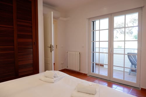 Quarto claro com roupa de cama branca no hotel Be SilverCoast em Serra d'El Rei, Portugal, com portas-janelas abertas para
