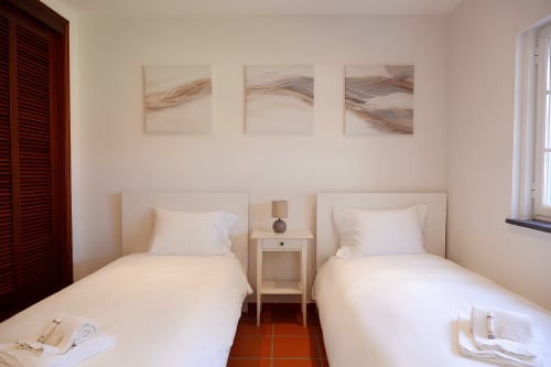 Quarto twin do hotel Be SilverCoast em Serra D'El Rei com duas camas de solteiro, criado de madeira e arte de parede abstrata