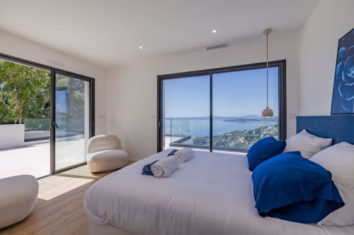 Chambre luxueuse avec vue sur mer à la Villa Prestige Azur Antilles, lit double, accents bleus et baies vitrées panoramiques