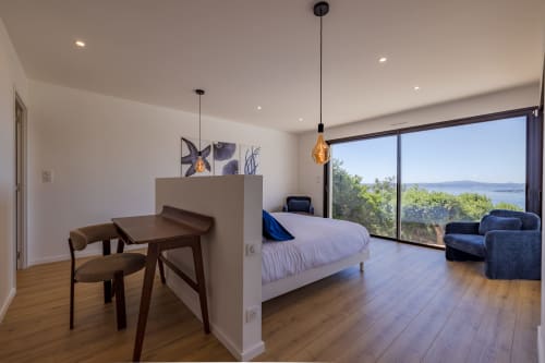 Chambre spacieuse de la villa Perle d'Azur avec vue mer, parquets, lit moderne, coin repas et balcon panoramique
