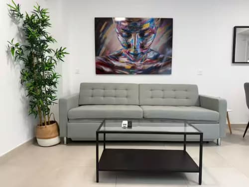 Luminoso salón de apartamento frente al mar con sofá gris, mesa de centro de cristal y arte colorido en Fuengirola