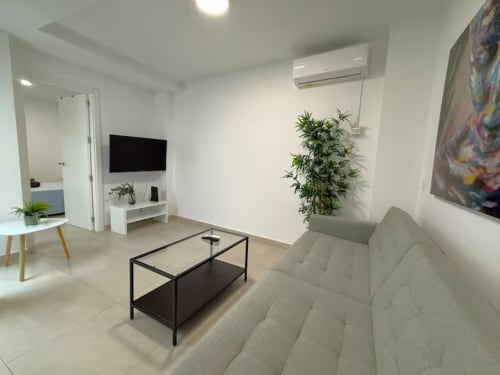 Acogedor apartamento moderno en la playa de Fuengirola con cómodos asientos, televisor, plantas y mobiliario contemporáneo