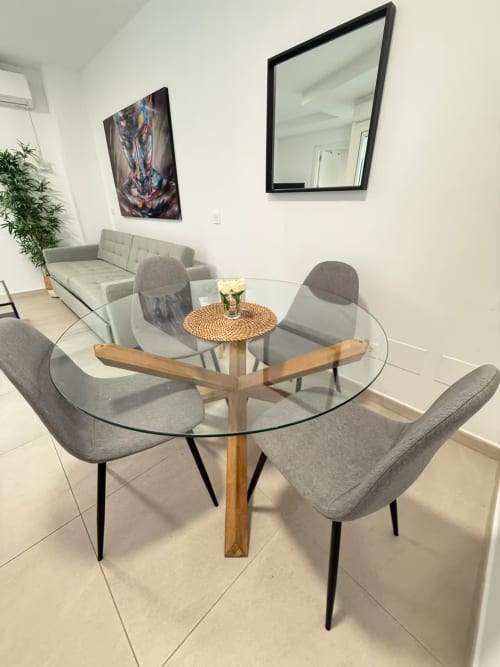 Área de comedor del moderno apartamento de playa en Fuengirola con mesa de cristal, sillas grises, sofá y obras de arte