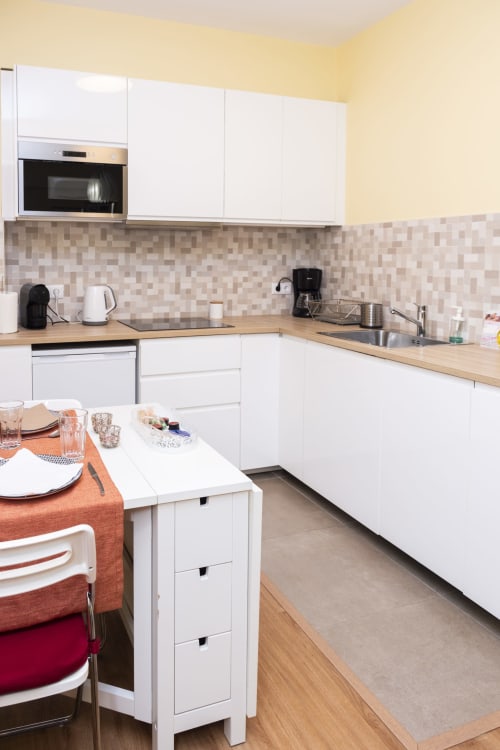 Modern white kitchen with wooden countertops, beige tile backsplash, and dining area at RH Charming Apartments Braga